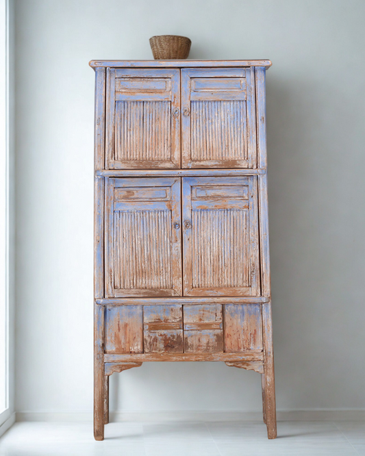 Light blue wooden tall cabinet with bamboo panels with basket on top