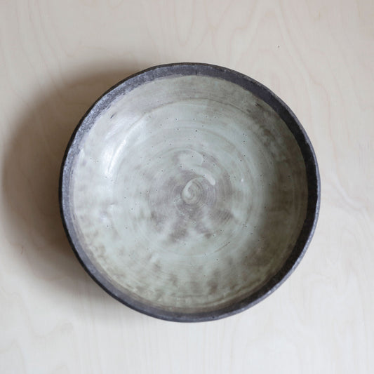 Side view of shallow bowl has an earthy organic look, with soft browns and cream and a beautiful smooth texture like tumbled pebbles. The inside depicts a wonderful concentric swirl.
