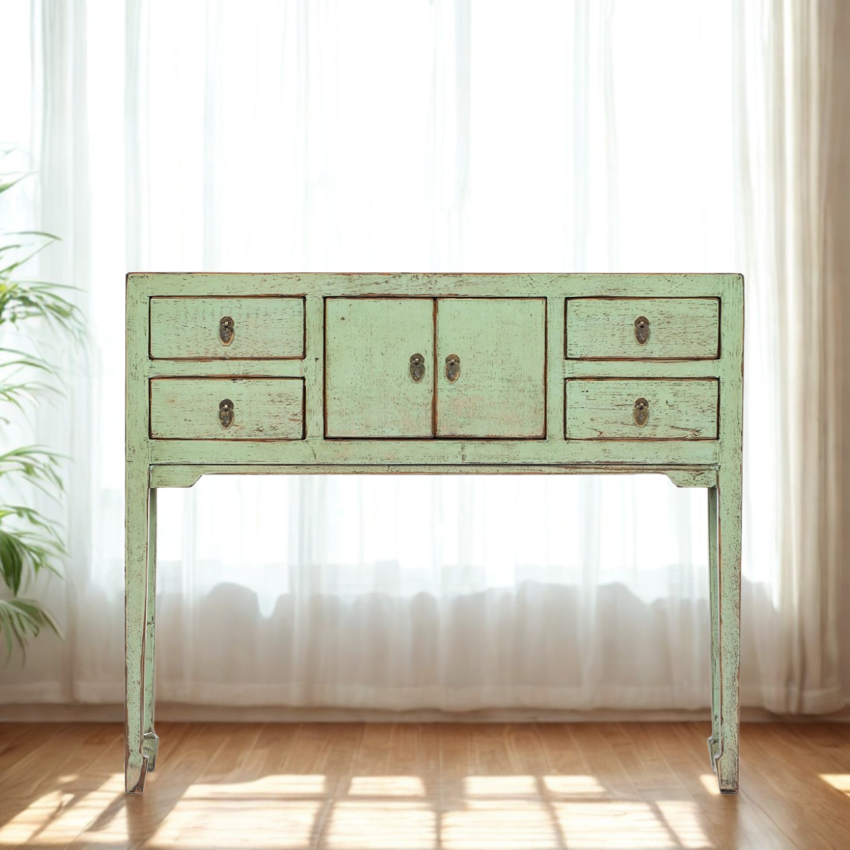 Vintage mint green console table with four drawers against a white curtain background