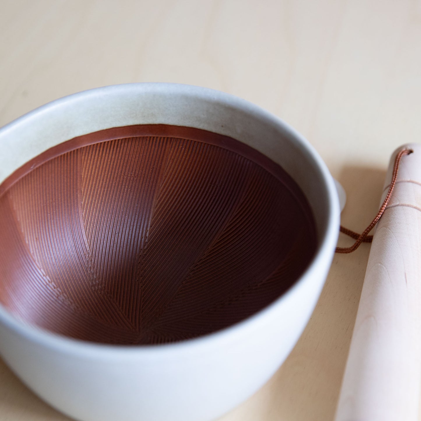 White ceramic bowl with brown interior on a beige surface