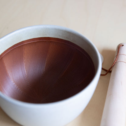 White ceramic bowl with brown interior on a beige surface
