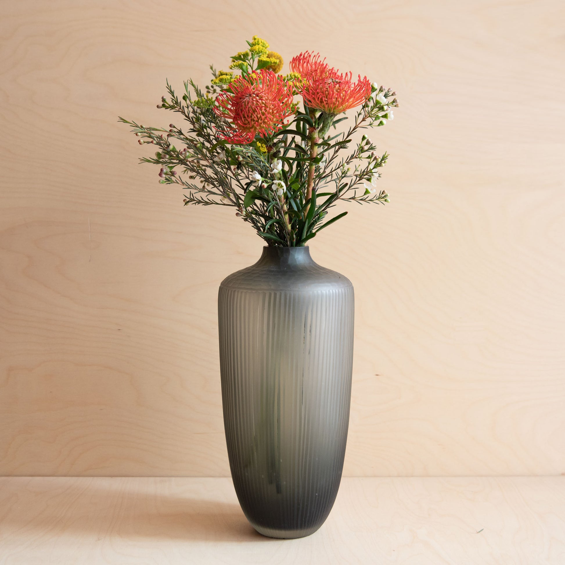 Gray textured vase with flowers on a beige background