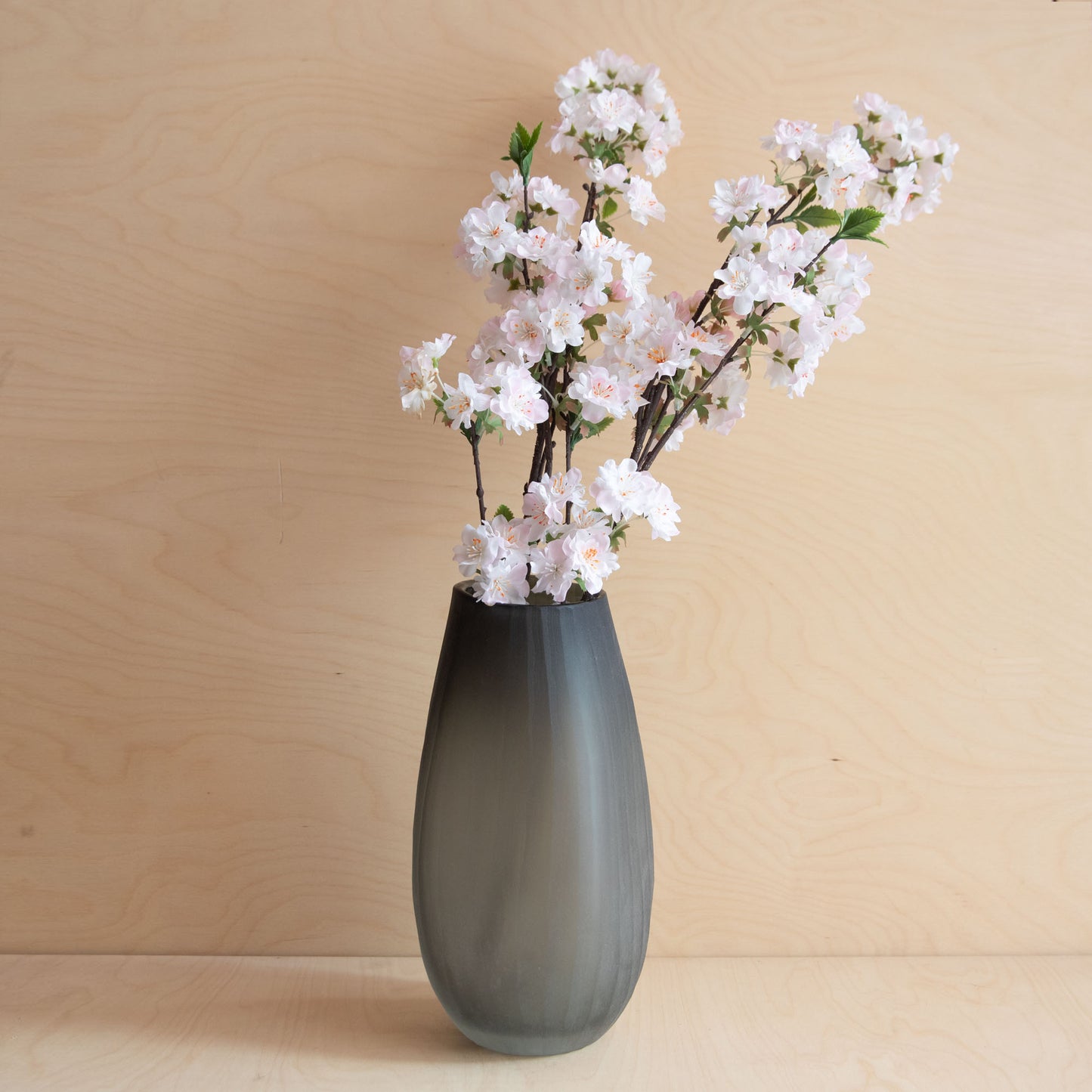 Gray vase with white flowers on a wooden surface and background