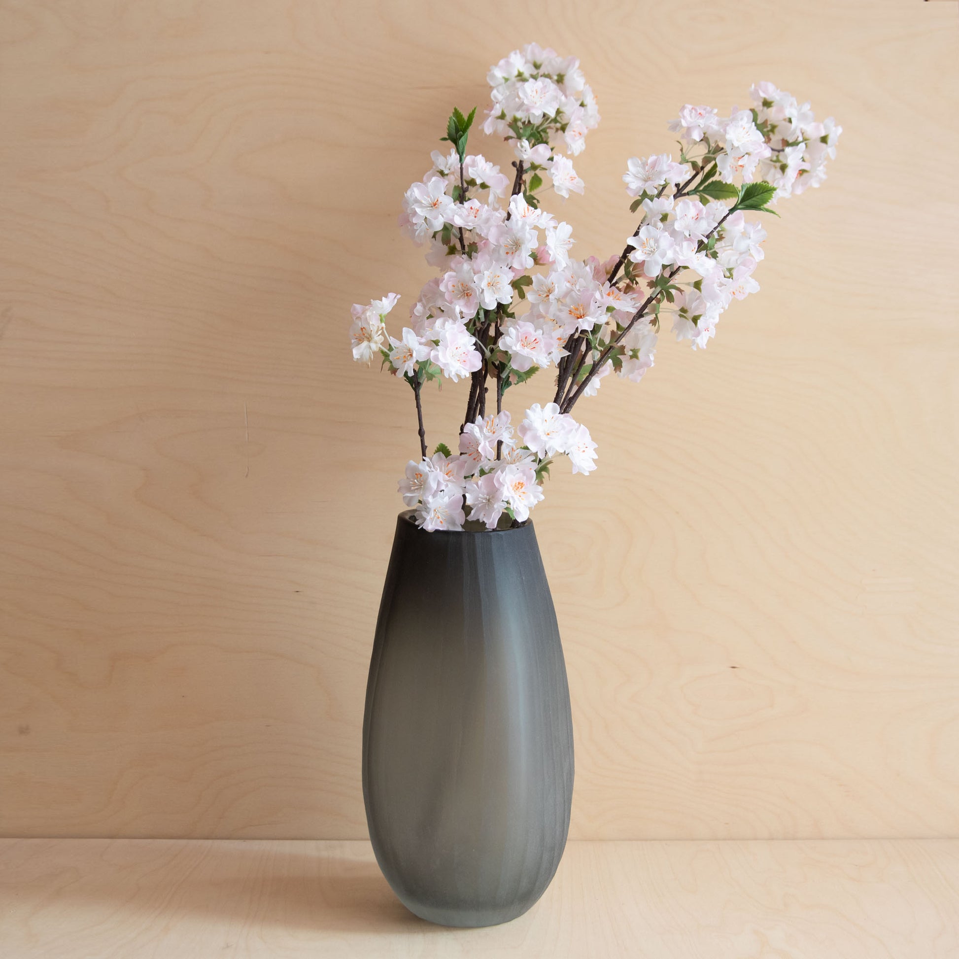 Gray vase with white flowers on a wooden surface and background