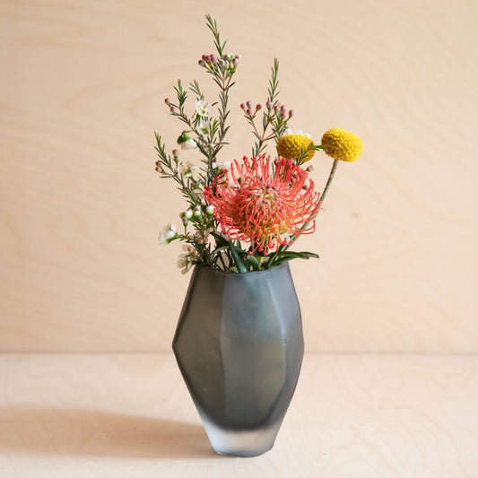 Gray vase with colorful flowers on a beige background